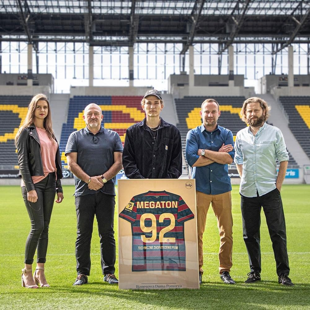 Przedstawiciele Megaton na stadionie w Szczecinie z pamiątkową koszulką z numerem 92